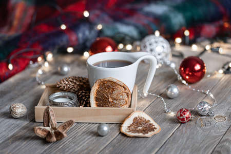 Cozy winter composition with a cup of hot drink, decorative details and Christmas balls on a blurred background with bokeh.の写真素材