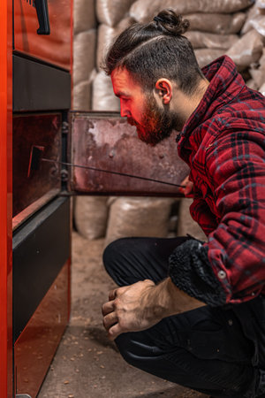 A man in a room with a solid fuel boiler, working on biofuel, economical heating.