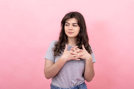 Attractive modest brunette girl in casual clothes on a pink background.