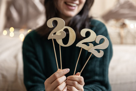 Close-up of wooden numbers 2022 on sticks in the hands of a girl, on a blurred background.
