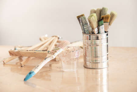 Tin can with paint brushes on a workshop table on a blurred background.の写真素材