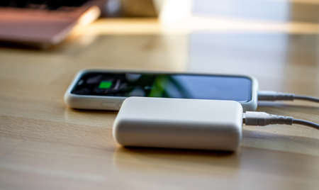 A smartphone is charged from a small white power bank.の写真素材