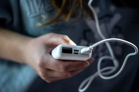 Close-up of a white power bank in a female hand.の写真素材
