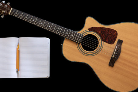 Classical acoustic guitar and an open notebook on a black background.