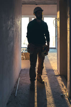A man builder in work clothes with a protective helmet at a construction site.の写真素材