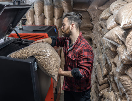 The man loads the pellets in the solid fuel boiler, working with biofuels.