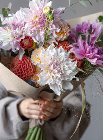 Close-up of a beautiful bouquet with chrysanthemums in female hands.の写真素材