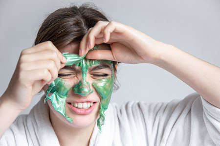 Removing a green cosmetic mask from the attractive girl face.の写真素材
