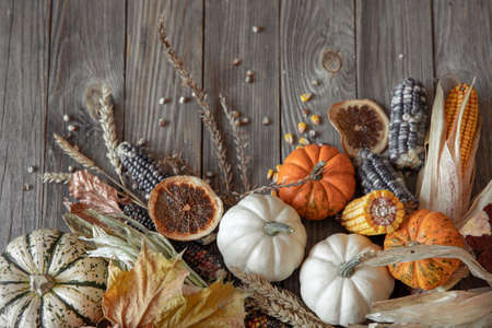 Autumn composition with pumpkins, corn and leaves on a wooden background.の写真素材