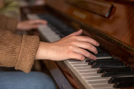 Close-up of female hands playing the piano.の写真素材