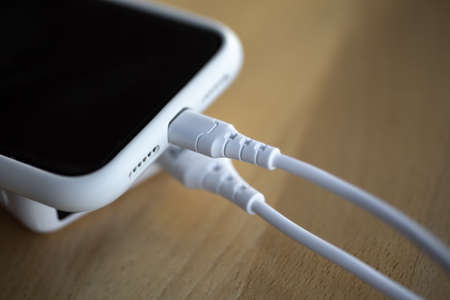 A smartphone is charged from a small white power bank.の写真素材