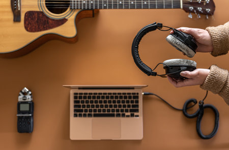 Music background with headphones in female hands, recorder, laptop and guitar.