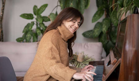 An attractive young woman plays the piano.の写真素材