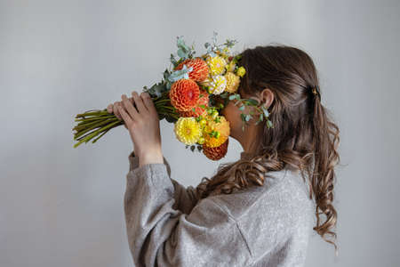 Young woman with a bouquet of fresh chrysanthemums on a gray background.の写真素材