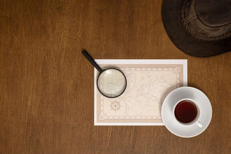 World map, magnifier and coffee on a wooden background, flat lay.の写真素材