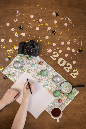 Christmas travel flat lay with numbers 2022, map, camera and white sheet.