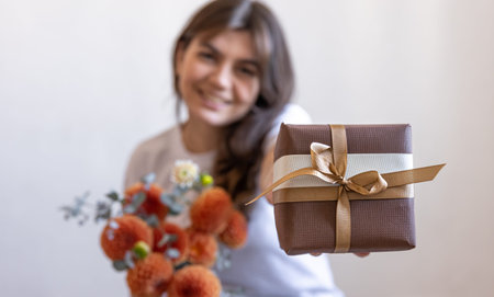 Young woman with a gift box and a bouquet of chrysanthemum flowers.