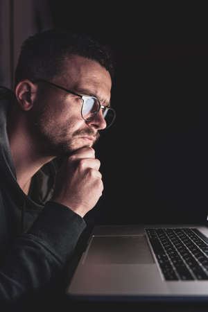 A man with glasses works at a computer late at night.の写真素材