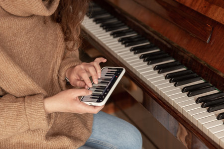 A woman learns to play the piano using an application on her phone.