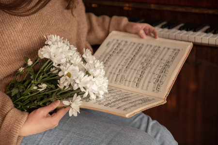 Close-up of music notes and a bouquet of flowers in female hands.
