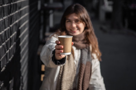 Close-up of a paper cup of hot drink in female hands.の写真素材