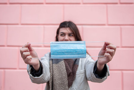 Young woman with a protective mask on the background of the wall.