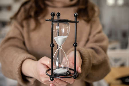Vintage glass hourglass close-up in female hands.の写真素材