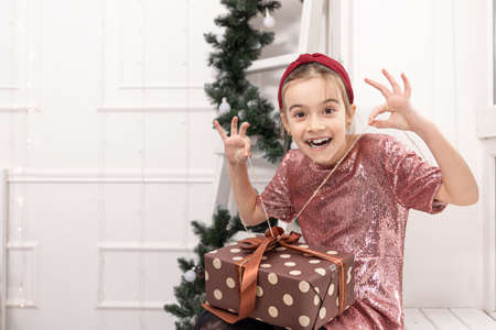 Funny little girl with a Christmas gift box.の写真素材