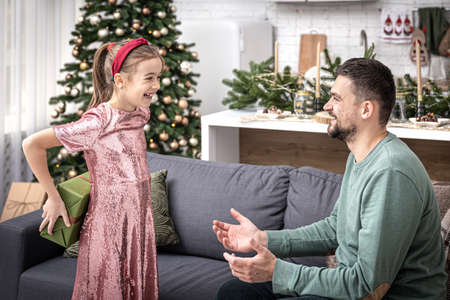 Little girl gives dad a festive Christmas present.の写真素材