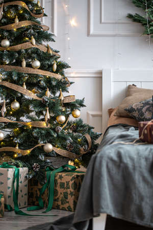 Interior of a cozy room with a Christmas tree and a gift box on the bed.の写真素材