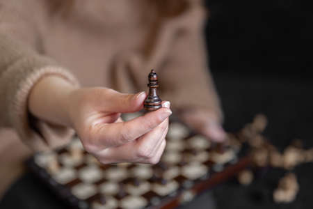 Close-up of a chess piece in female hands, blurred background.の写真素材