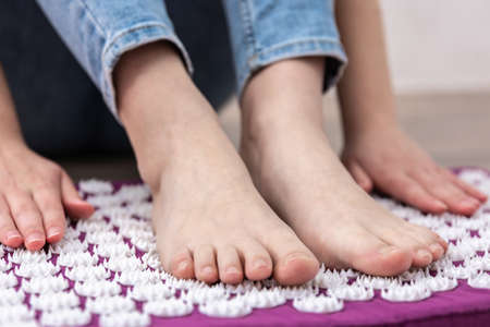 Purple massage acupuncture mat and white massage tips in female hands.の写真素材