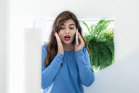 Attractive young woman talking on the phone in a white interior, copy space.