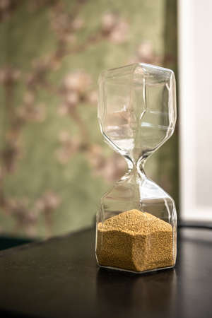 Close up of glass hourglass on blurred background.の写真素材