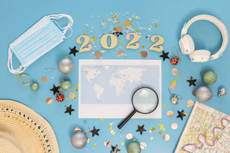 Travel flat lay composition with world map and numbers 2022 on blue background.の写真素材