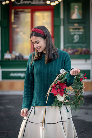 Stylish young woman with a Christmas wreath in red and green colors.の写真素材