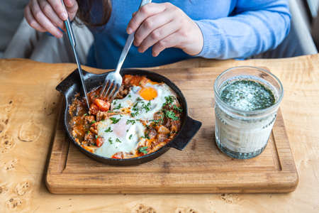 Close-up, a woman in a cafe dines on traditional shakshuka.の写真素材
