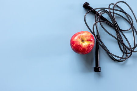 Jump rope and apple isolated on blue, copy space.の写真素材