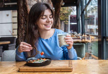 A young woman in a cafe dines on traditional shakshuka and ayran.の写真素材