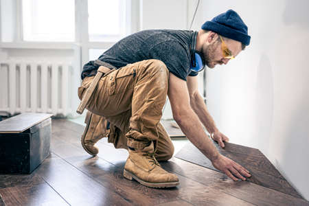 A male worker puts laminate flooring on the floor.の写真素材