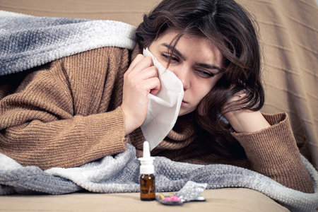 Sick young woman with medicines lies in bed, colds and home treatment.の写真素材