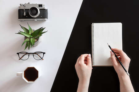 Flat lay composition with hands and blank notepad on black and white background.の写真素材