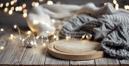 Cozy background with knitted element on a wooden element and bokeh lights.