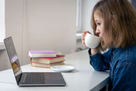 Teen girl sits in front of a laptop, online learning.の写真素材