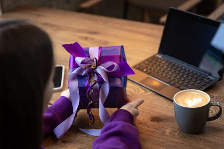 Purple gift box in a womans hands in a purple sweater.の写真素材