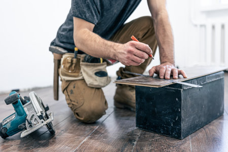 A male worker puts laminate flooring on the floor.の写真素材