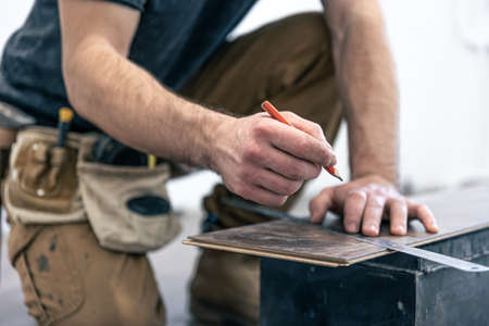 A male worker puts laminate flooring on the floor.の写真素材