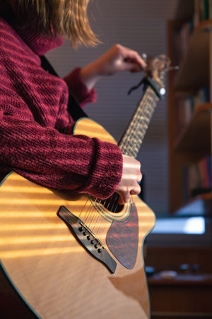 Girl with a guitar in the sunlight through the blinds.