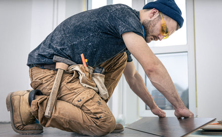 A male worker puts laminate flooring on the floor.