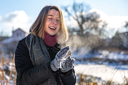 Happy young woman on a walk in winter with snow in her hands.の写真素材